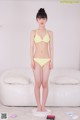 A woman in a yellow bikini standing on a scale.